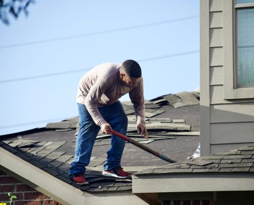 Professional roofing contractor examining shingles on a Pacific Northwest home - roof inspection frequency for pacific