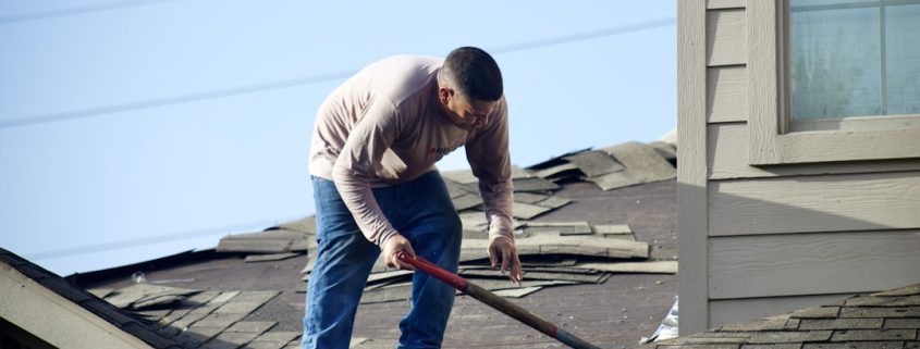 Professional roofing contractor examining shingles on a Pacific Northwest home - roof inspection frequency for pacific