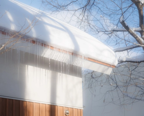 snow-covered roof with large icicles and ice dams forming at eaves - how ice dams form and what to do about them