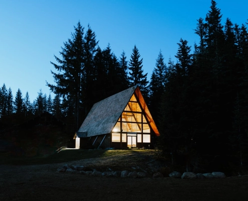 Pacific Northwest home with rain falling on roof surrounded by tall evergreen trees